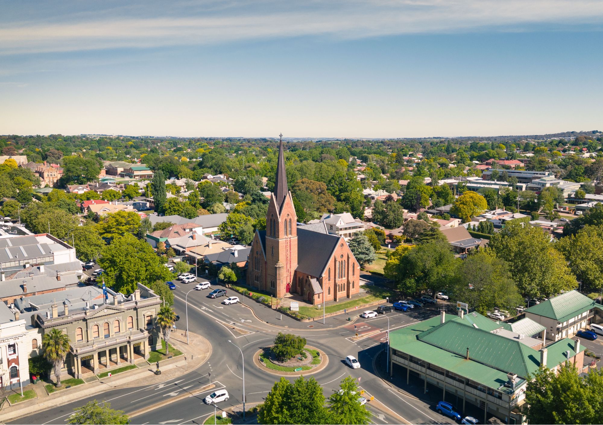 Aerial view of Orange NSW featuring historic church architecture, tree-lined streets, and the vibrant regional city surrounded by gardens and heritage buildings.