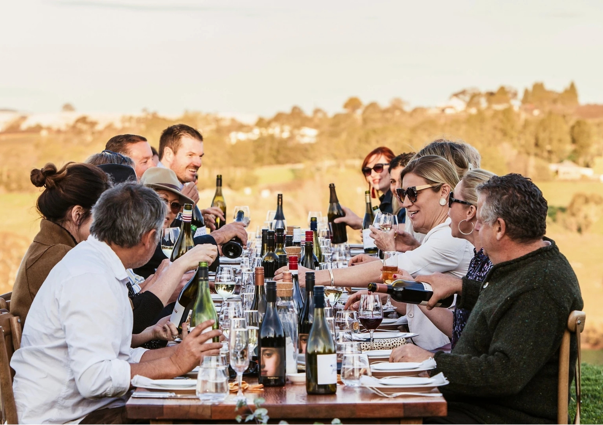 Guests enjoying wine and conversation around a long outdoor dining table overlooking the vineyards during the Orange Wine Festival in Orange, NSW.